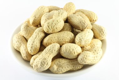 Avuç dolusu fıstık kabuğu üzerinde bir beyaz porselen tabak 