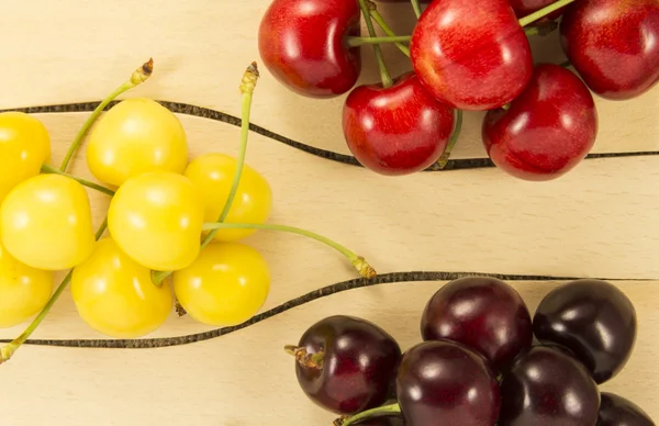 Colorful cherries in a wooden spatula on a natural fabric — Stock Fotó
