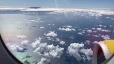 Uçak uçuşu. La Palma, Kanarya Adaları 'nda bulutların ve denizin üzerinde uçan bir uçağın kanadı. Uçağın penceresinden bak. 4K UHD