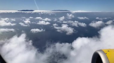 Uçak uçuşu. La Palma, Kanarya Adaları 'nda bulutların ve denizin üzerinde uçan bir uçağın kanadı. Uçağın penceresinden bak. 4K UHD