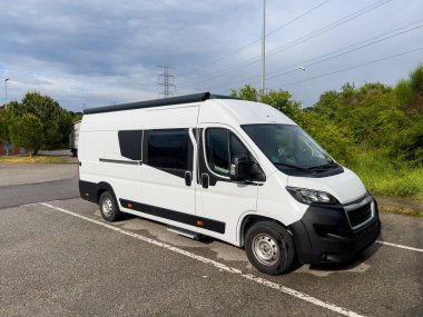 Vacarisses 'teki bir otoparkta park etmiş beyaz karavan yaz yolculuğuna hazır.