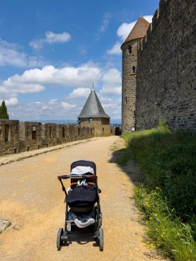 Carcassonne 'un tarihi surlarında güneşli bir gökyüzünün altında boş bir bebek arabası ortaçağ mimarisi manzarası sunuyor.
