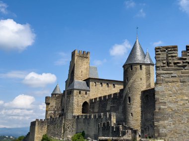 Carcassonne 'un ortaçağ tahkimatları şehrin zengin tarihi ve mimari ihtişamını gözler önüne seren canlı mavi gökyüzüne karşı dimdik ayakta duruyor.