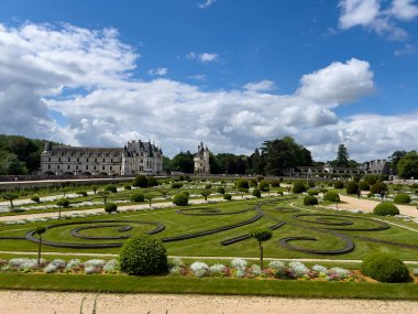 Fransa 'nın Loire Vadisi' ndeki Chenonceaux Kalesi 'nin önündeki çiçeklerle süslü bahçe, bulutlu açık mavi bir gökyüzünün altında.