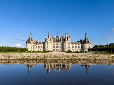 Majestic Chambord Şatosu, güneşli bir günde, Cosson Nehri 'nin sakin sularında yansıdı.