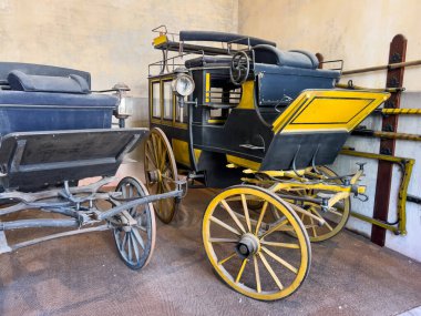 İki antika at arabası, biri sarı ve siyah, diğeri koyu mavi, Chaumont sur Loire, Fransa 'da bir ahırda korunmuş.