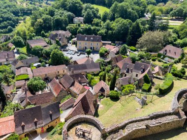 Kale 'den Castelnaud la Chapelle köyünün panoramik manzarasında Dordogne, Fransa' da geleneksel evler ve yemyeşil alanlar sergileniyor.