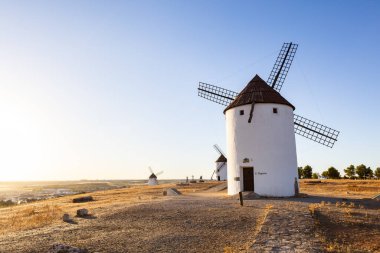 Geleneksel İspanyol yel değirmenleri, La Mancha 'da güzel bir gün batımında kuru bir tepede dururlar.