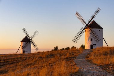 Geleneksel yel değirmenleri berrak bir gökyüzüne karşı gün batımında huzurlu kırsal alanı yakalıyorlar.