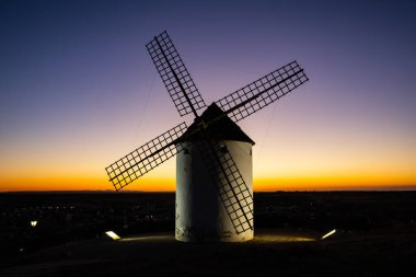 Geleneksel İspanyol yel değirmeni canlı bir alacakaranlık gökyüzüne karşı aydınlandı. Seyahat tarihini simgeliyor.