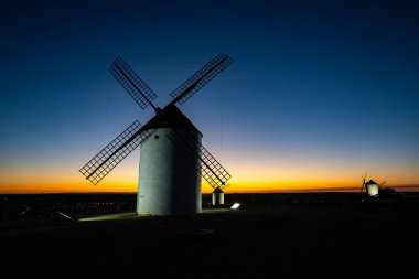 Geleneksel İspanyol yel değirmenleri Mota del Cuervo 'da canlı bir alacakaranlık gökyüzüne karşı duruyorlar.
