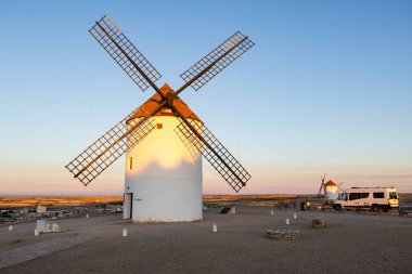 Yel değirmeni ve park etmiş karavan gün batımında Mota del Cuervo manzarasını izliyor