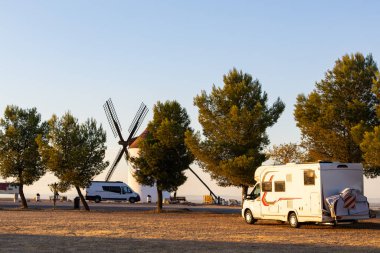 Kamp arabası ve karavan güneş batarken geleneksel İspanyol yel değirmenlerinin yakınına park edilmiş.