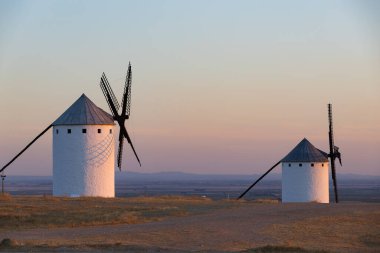 Geleneksel İspanyol yel değirmenleri rengarenk bir günbatımında tepenin üzerinde duruyor, kültürel tarihi gösteriyorlar.