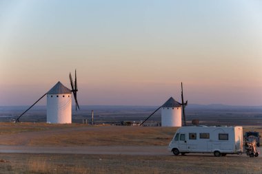 Kamp aracı Campo de Criptana, İspanya 'da günbatımında tarihi yel değirmenlerinin yakınına park edilmiş.