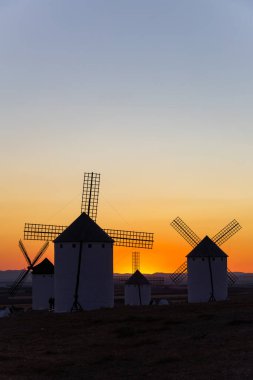 Canlı turuncu ve mavi gün batımına karşı durmakta olan tarihi İspanyol yel değirmenleri