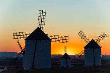 Geleneksel İspanyol yel değirmenleri La Mancha 'da bir akşam gün batımında turuncu bir gökyüzüne karşı duruyorlar.