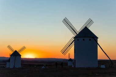 İspanya, La Mancha 'da canlı bir günbatımına karşı siluet gibi duran yel değirmenleri