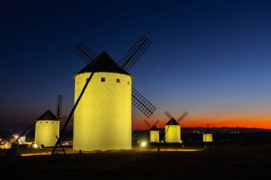 İspanyol yel değirmenleri La Mancha 'daki alacakaranlık gökyüzüne karşı sararmış.