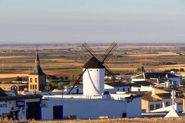 Geleneksel beyaz evlere ve geniş La Mancha ovalarına bakan bir tepede duran yel değirmeni.