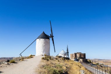 İspanya, Consuegra 'da bir tepenin üzerinde duran tarihi beyaz yel değirmenleri ve şato