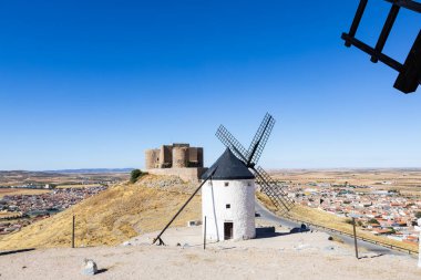 İspanya 'nın La Mancha kentindeki Consuegra kasabasına bakan bir tepenin üzerinde yel değirmenleri ve şato duruyor.