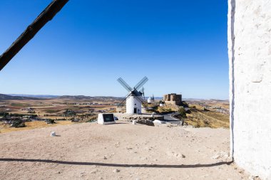 Beyaz yel değirmenleri ve İspanya 'nın Consuegra kentindeki tarım arazilerine bakan bir tepenin üzerinde duran bir kale.