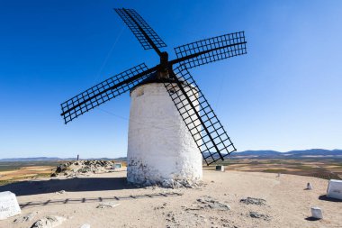 Kuru bir tepenin üzerinde duran yel değirmeni geniş bir kırsal alana bakıyor.