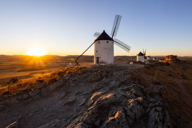 İspanya 'da seyahat ve turizmi yansıtan altın saat ışığıyla aydınlatılan tarihi rüzgar değirmenleri ve şato
