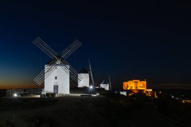 Consuegra yel değirmenleri ve şatosu bir tepenin üzerinde aydınlandı ve tarihi bir gece manzarası yarattı.