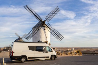 Tepedeki karavan Consuegra, Kastilya, La Mancha, İspanya 'daki tarihi yel değirmenlerine bakıyor.