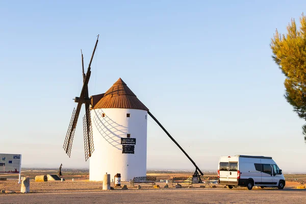 İspanya, La Mancha 'da günbatımında tarihi bir yel değirmeninin yanına park edilmiş bir karavan.