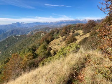 Sonbahar yapraklı engin dağ manzarası mavi gökyüzünün altında bir yürüyüş yolu boyunca.