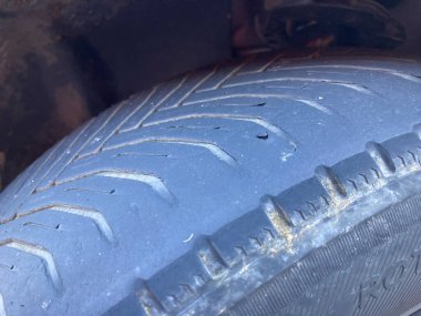 Yıpranmış lastik ve lastik çatlaklarından dolayı yenilenmesi gereken eski bir arabanın lastiğini kapat.