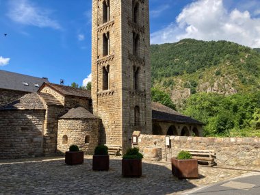 Sant Climent kilise çan kulesi arka planda dağlar olan kaldırımlı bir plazanın üzerinde duruyor.