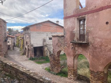 Antik taş binalar ve tarihi bir İspanyol köyündeki kırsal yaşamı tasvir eden bir kaldırım taşı caddesi.