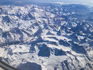 Çerçeveleri dolduran karlı dağlar, havadan dağ manzarası gösteriyor.