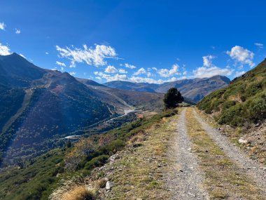 Porte Puymorens 'de açık mavi gökyüzünün altında bir dağ yamacını geçen toprak yol.
