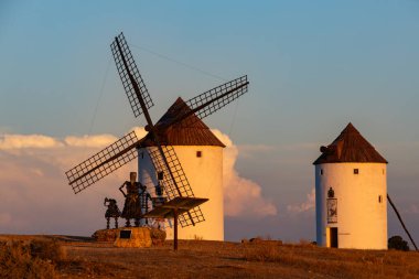 Sıcak akşam güneşiyle yanan bir tepede duran klasik beyaz yel değirmenleri.