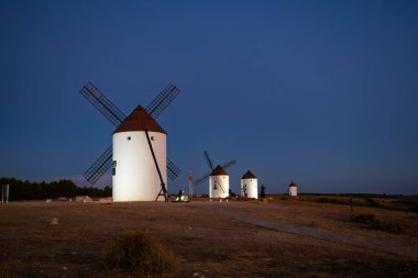Akşam karanlığında kuru arazide duran yel değirmenleri İspanyol geleneğini ve Don Kişot 'u temsil ediyor.