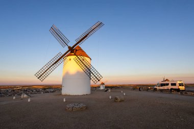 Kasabanın ve tarihi yel değirmenlerinin yakınındaki tepede park etmiş karavan La Mancha 'da günbatımını yaşıyor.