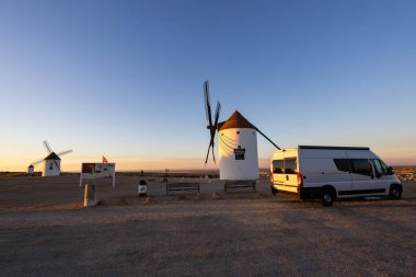 Campervan, gün doğumunda yel değirmenlerinin yakınına park etmiş. La Mancha 'da macerayı ve seyahati temsil ediyor.