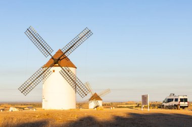 Altın saatinde geleneksel Mota del Cuervo yel değirmenlerinin yakınına park edilmiş bir karavan.