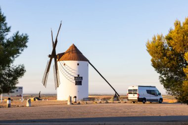 İspanya 'nın Mota del Cuervo kentindeki geleneksel bir rüzgar değirmeninin yakınına park edilmiş bir Campervan.