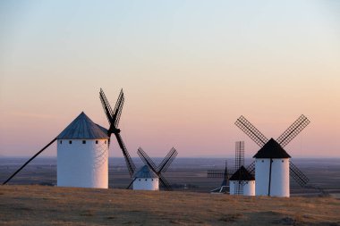 Geleneksel yel değirmenleri Güneş batarken tarihi La Mancha manzarasını tanımlıyor