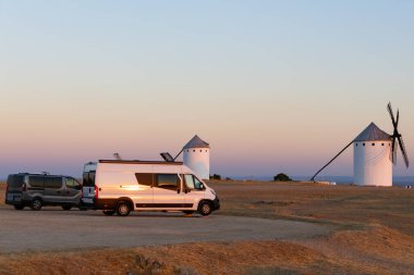 Kamp araçları Castilla La Mancha, İspanya 'da ikonik yel değirmenleri üzerinde güzel bir günbatımına tanıklık ediyor.