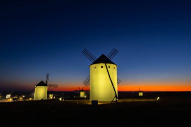 On sekizinci yüzyıl İspanyol yel değirmenleri alacakaranlıkta canlı bir günbatımı gökyüzünün altında parlıyordu.