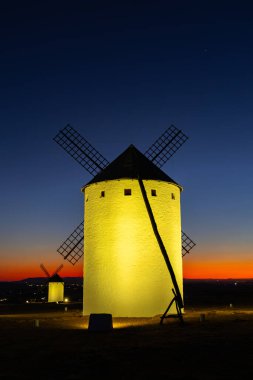 Alacakaranlıkta parlayan tarihi yel değirmenleri La Mancha 'nın mimari mirasının güzelliğini sergiliyor.