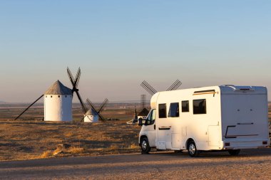 Kamp minibüsü Campo de Criptana, İspanya 'da altın saatinde klasik yel değirmenleriyle park edilmiş.