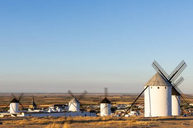 Kasabaya bakan geleneksel yel değirmenleri ve güzel bir gökyüzünün altındaki La Mancha manzarası
